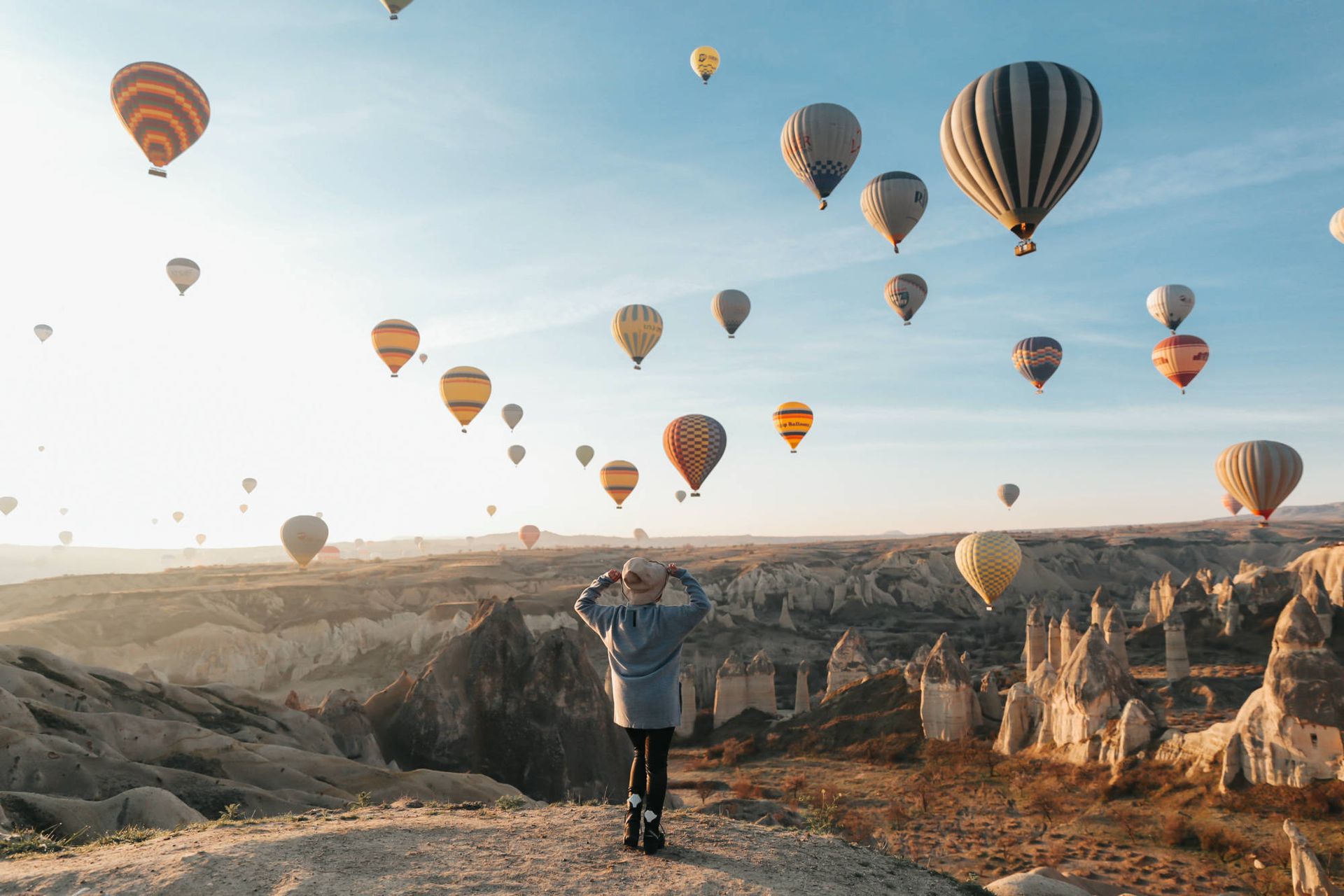 Traveler watching dozens of hot-air balloons rise over Cappadocia at sunrise