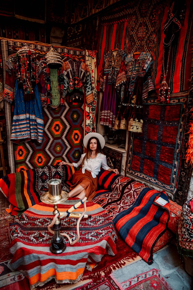 A guest photographed among colourful carpets and glowing mosaic lanterns inside a traditional Cappadocia carpet shop, the team's indoor option for a snowy or rainy winter morning